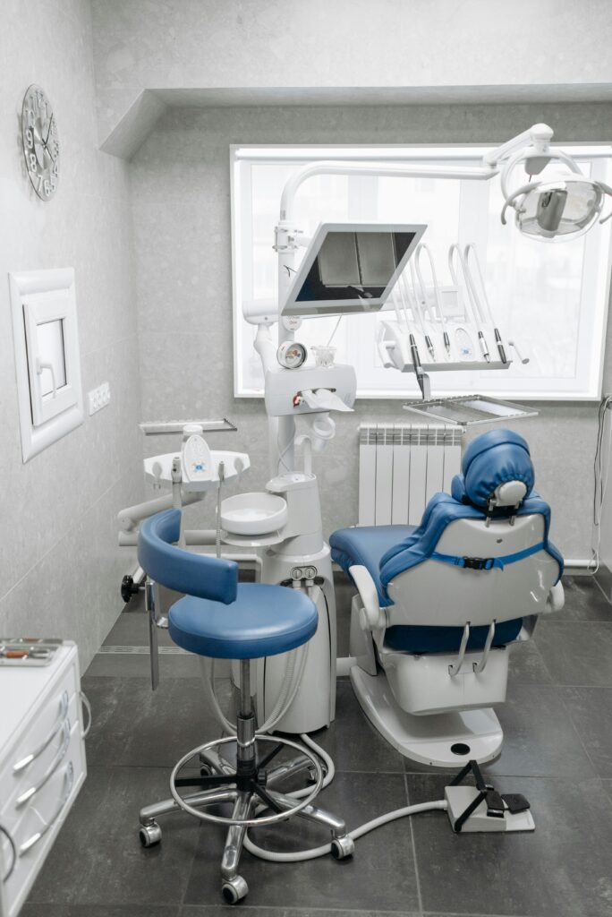 A clean and modern dental office featuring a dental chair, equipment, and bright lighting.